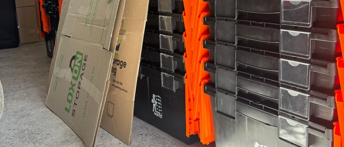 Stacked Move Mate crates standing next to cardboard sheets leaning against a wall