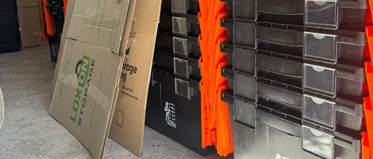 Stacked Move Mate crates standing next to cardboard sheets leaning against a wall