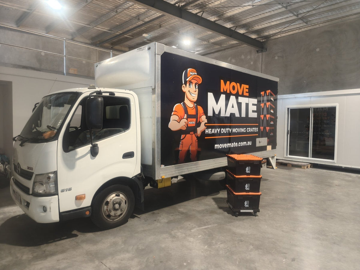 Move Mate truck parked in a large shed with a stack of crates in front