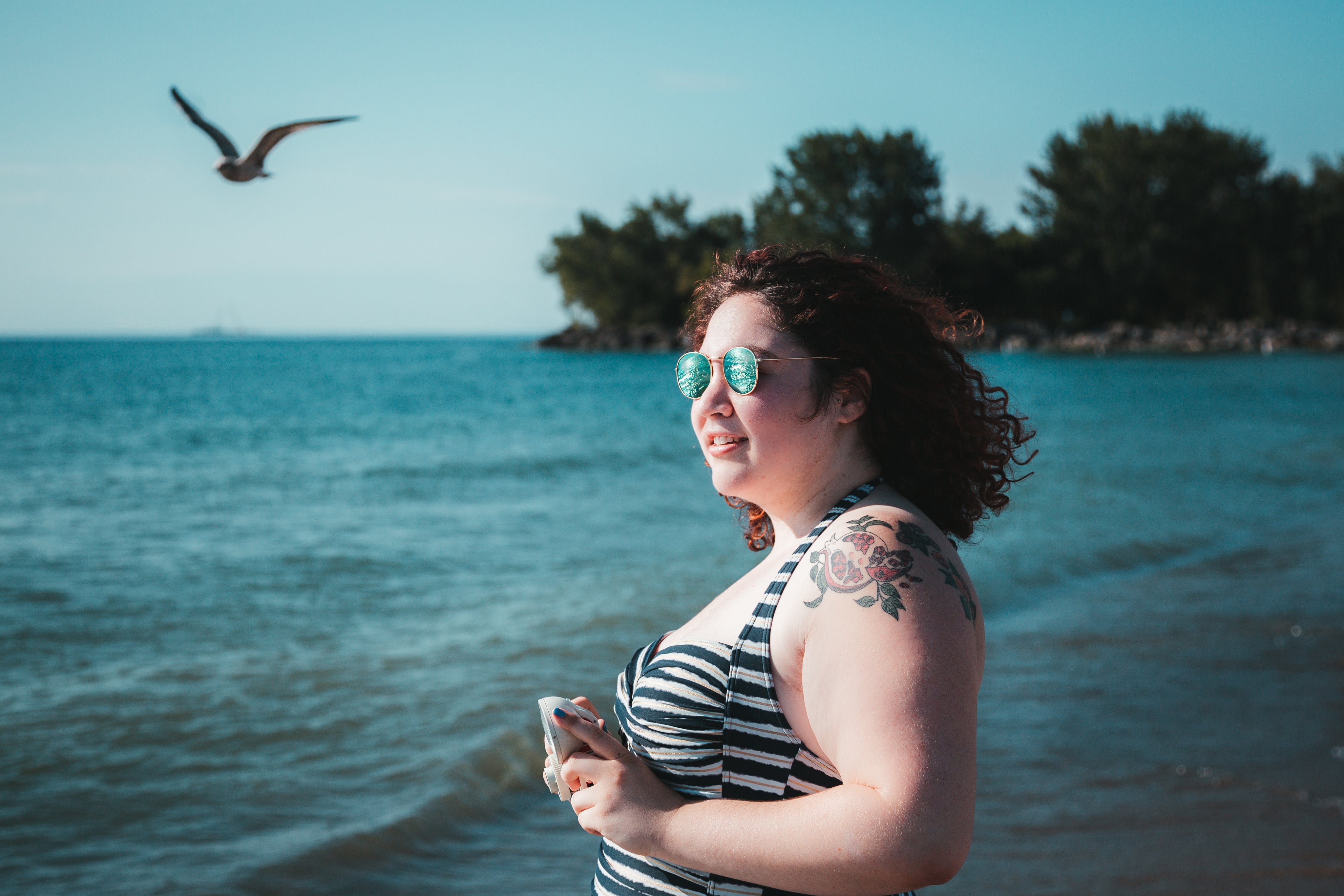 files/young-woman-in-sunglasses-holding-camera-facing-beach.jpg